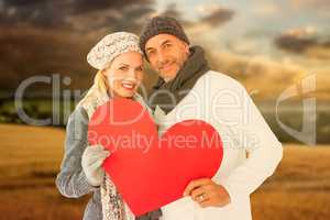 Composite image of portrait of happy couple holding heart