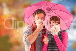 Composite image of couple standing underneath an umbrella