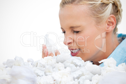 Composite image of ill woman sneezing into tissue