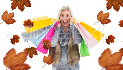 Composite image of blonde in winter clothes holding shopping bag