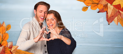 Composite image of happy couple forming heart with hands