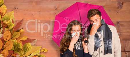 Composite image of couple blowing nose while holding umbrella