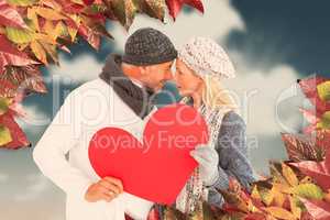 Composite image of couple holding heart while looking at each ot