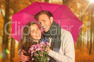 Composite image of cheerful young couple with flowers and umbrel