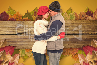 Composite image of happy couple in warm clothing hugging