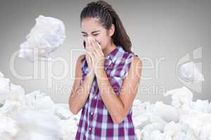 Composite image of sick blonde woman sneezing in a tissue