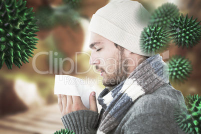 Composite image of handsome man in winter fashion blowing his no