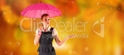 Composite image of pretty redhead businesswoman holding umbrella