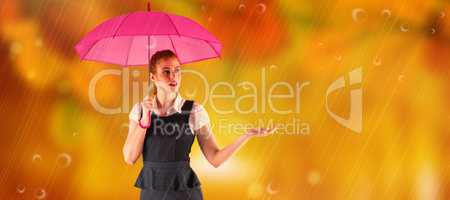 Composite image of pretty redhead businesswoman holding umbrella