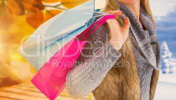 Composite image of blonde in winter clothes holding shopping bag