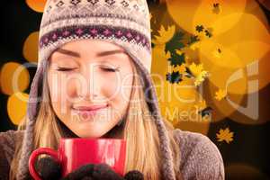 Composite image of happy blonde in winter clothes holding mug