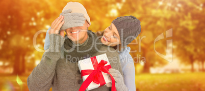 Composite image of woman surprising husband with gift