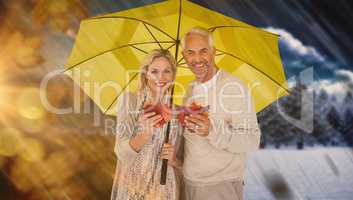 Composite image of portrait of happy couple under yellow umbrell