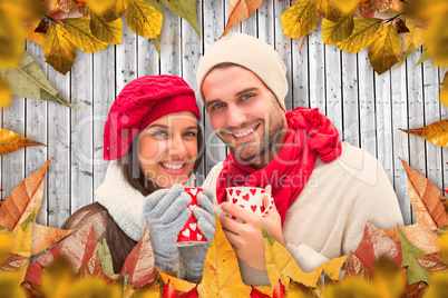 Composite image of winter couple holding mugs