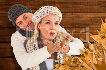 Composite image of husband hugging wife from behind as she blows