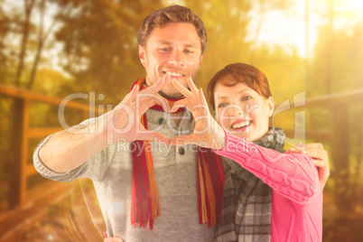 Composite image of couple making a heart shape