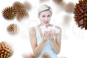 Composite image of sick woman holding tissues looking at camera