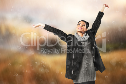 Composite image of pretty girl in winter jumper lifting arms