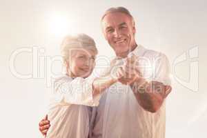 Composite image of senior couple dancing on the beach