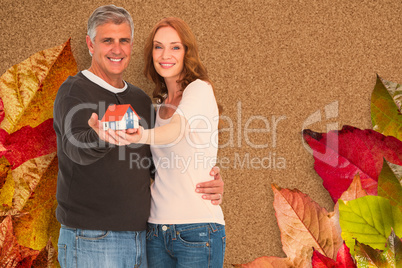 Composite image of casual couple holding small house