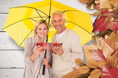 Composite image of portrait of happy couple under yellow umbrell