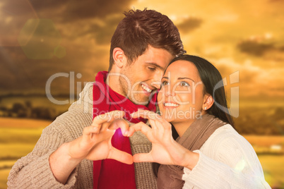 Composite image of young couple making heart with hands