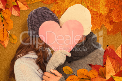 Composite image of couple in warm clothing holding heart