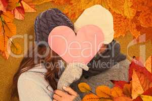 Composite image of couple in warm clothing holding heart