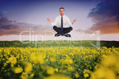 Composite image of businessman meditating in lotus pose