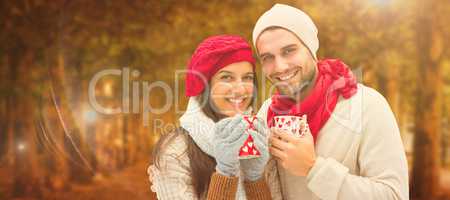 Composite image of winter couple holding mugs