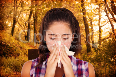 Composite image of close-up of sick woman sneezing in a tissue