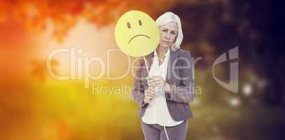 Composite image of  businesswoman holding sad smiley face
