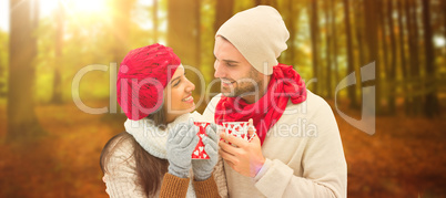 Composite image of winter couple holding mugs