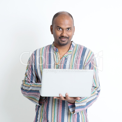 Mature casual Indian man using laptop
