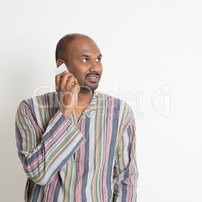 Mature casual Indian man talking on smartphone
