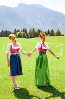 Mutter und Tochter beide im Dirndl gehen Hand in Hand spazieren.