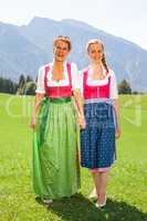 Mutter und Tochter beide im Dirndl gehen Hand in Hand spazieren.