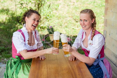 Zwei Frauen prosten sich mit einem Glas Bier zu