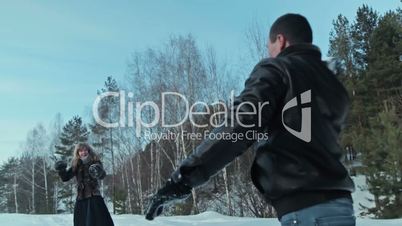 Couple having snowball fight in snow in winter forest, slowmotion