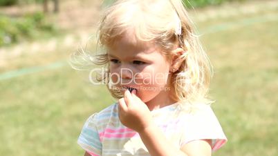 Lovely girl eating fresh blueberries in the garden