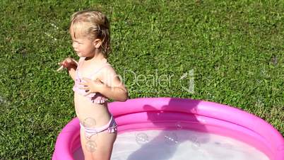 A delighted girl playing in a water-filled kiddie pool