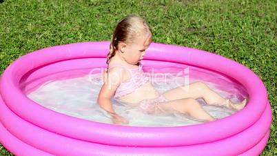 Little girl playing in a water filled kiddie pool