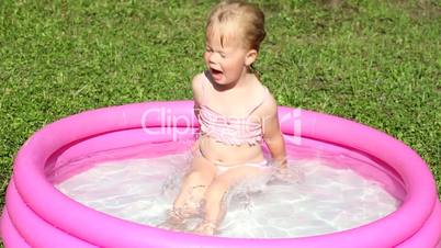 Little girl playing in a water filled kiddie pool