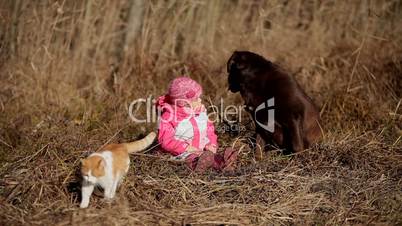 Little girl playing with a Brown Labrador retriever and a yellow cat in winter