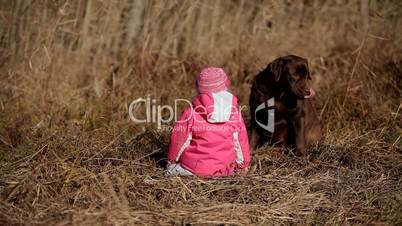 Little girl playing with a Brown Labrador retriever in winter