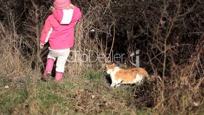 Little girl playing with a red cat in winter