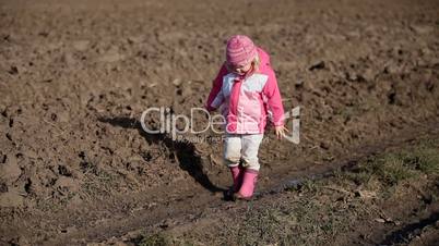 Little girl walking in mud, in puddle