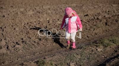 Little girl walking in mud, in puddle