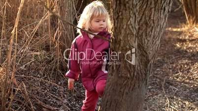 Adorable little girl playing with a twig in the nature in winter