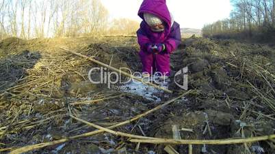 Little child playing with a stick on ice